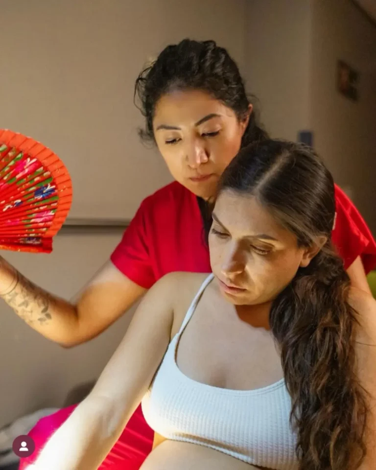 Doula acompaña con atención y respeto a mujer embarazada durante el trabajo de parto, creando un espacio seguro y cálido.