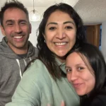 Mujer doula sonríe junto a una pareja después de haber acompañado su parto.
