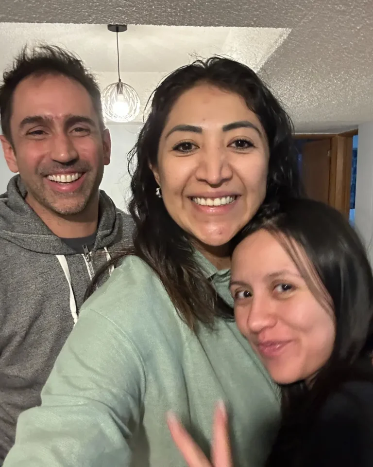 Mujer doula sonríe junto a una pareja después de haber acompañado su parto.